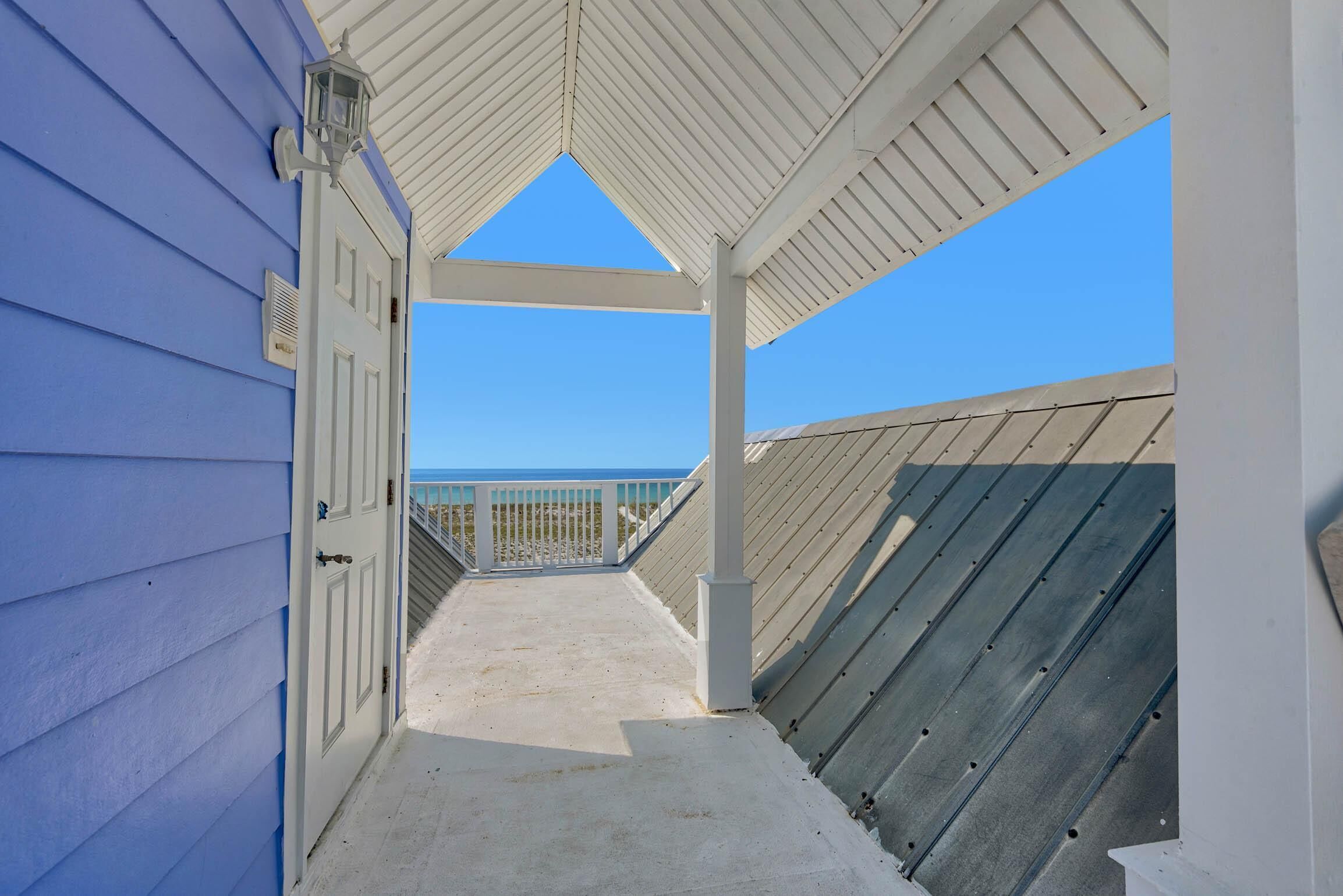 A covered walkway leading to a balcony with a view of the ocean.