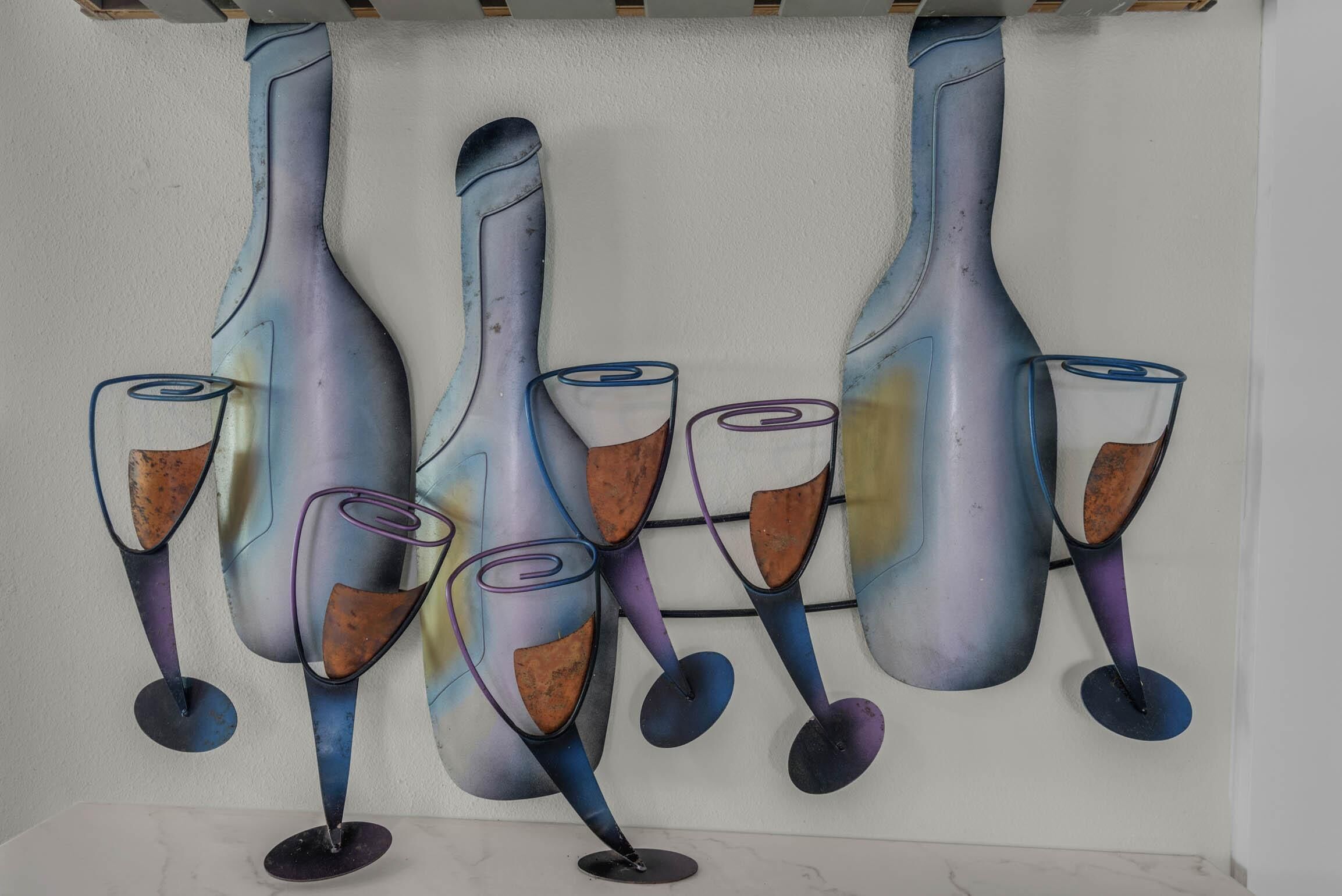Un mur décoré d’œuvres d’art abstraites représentant des bouteilles et des verres à vin.