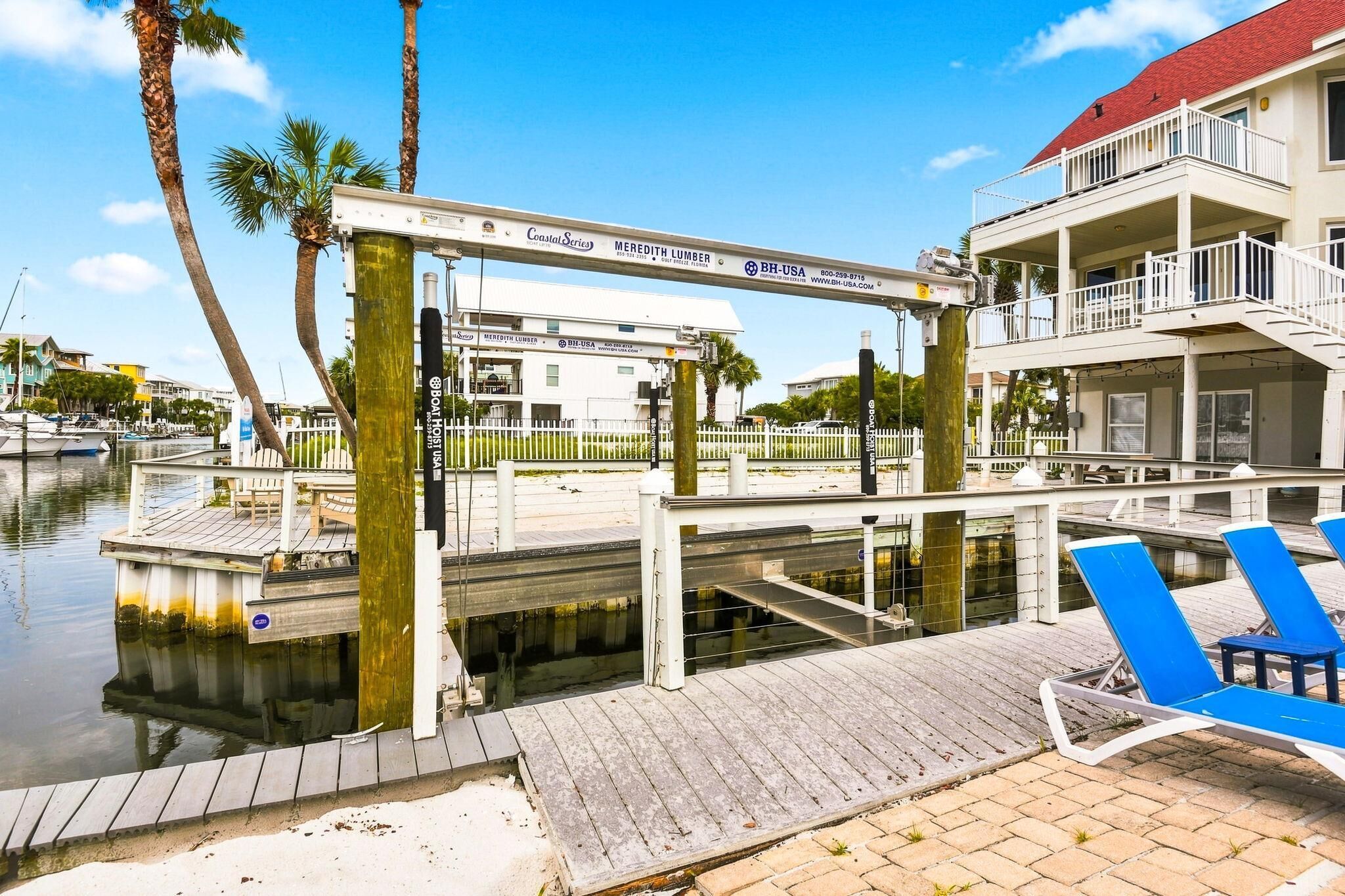 Een pand aan het water met een steiger, lounge fauteuils en balkons.