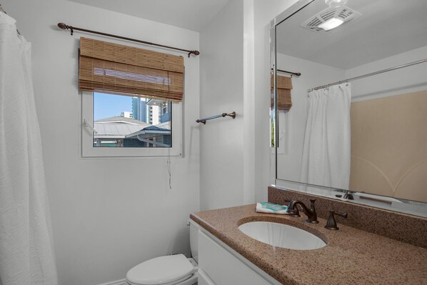 A bathroom with a window, a sink, and a mirror.