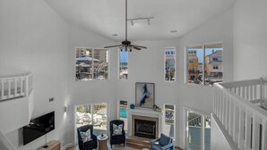 Uma sala de estar espaçosa com lareira, várias janelas com vista para a cidade e uma varanda com mobiliário de exterior.