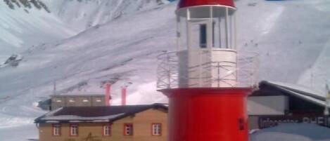 A red and white lighthouse with a clear view of a yellow building in the background.