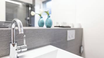 A modern bathroom with a chrome faucet, a white sink, and a mirror above it.