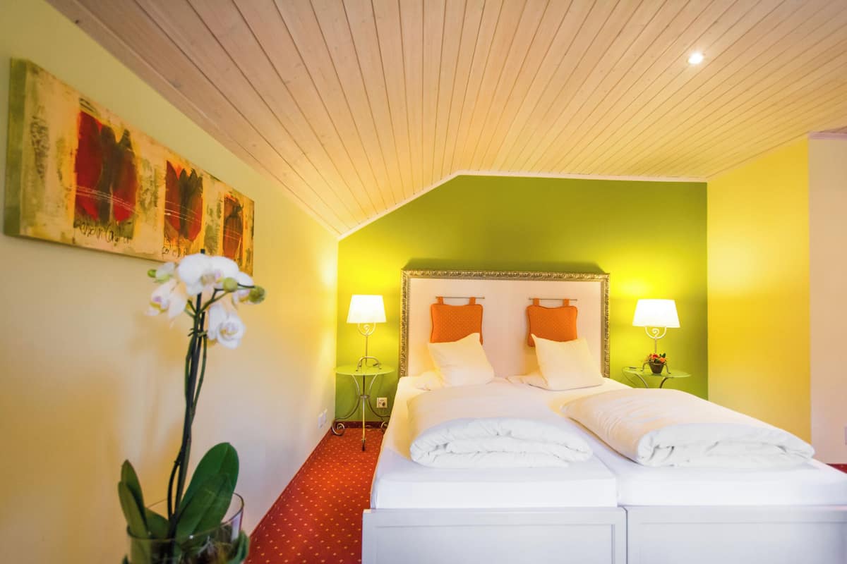 A hotel room with a bed, two bedside tables, a lamp, and a painting on the wall.