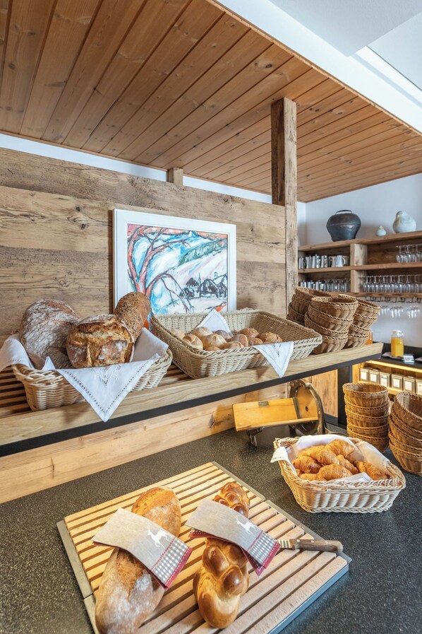 A bakery with various breads and pastries displayed on wooden tables and baskets. - La Cruna Hotel-Restaurant (Tujetsch)