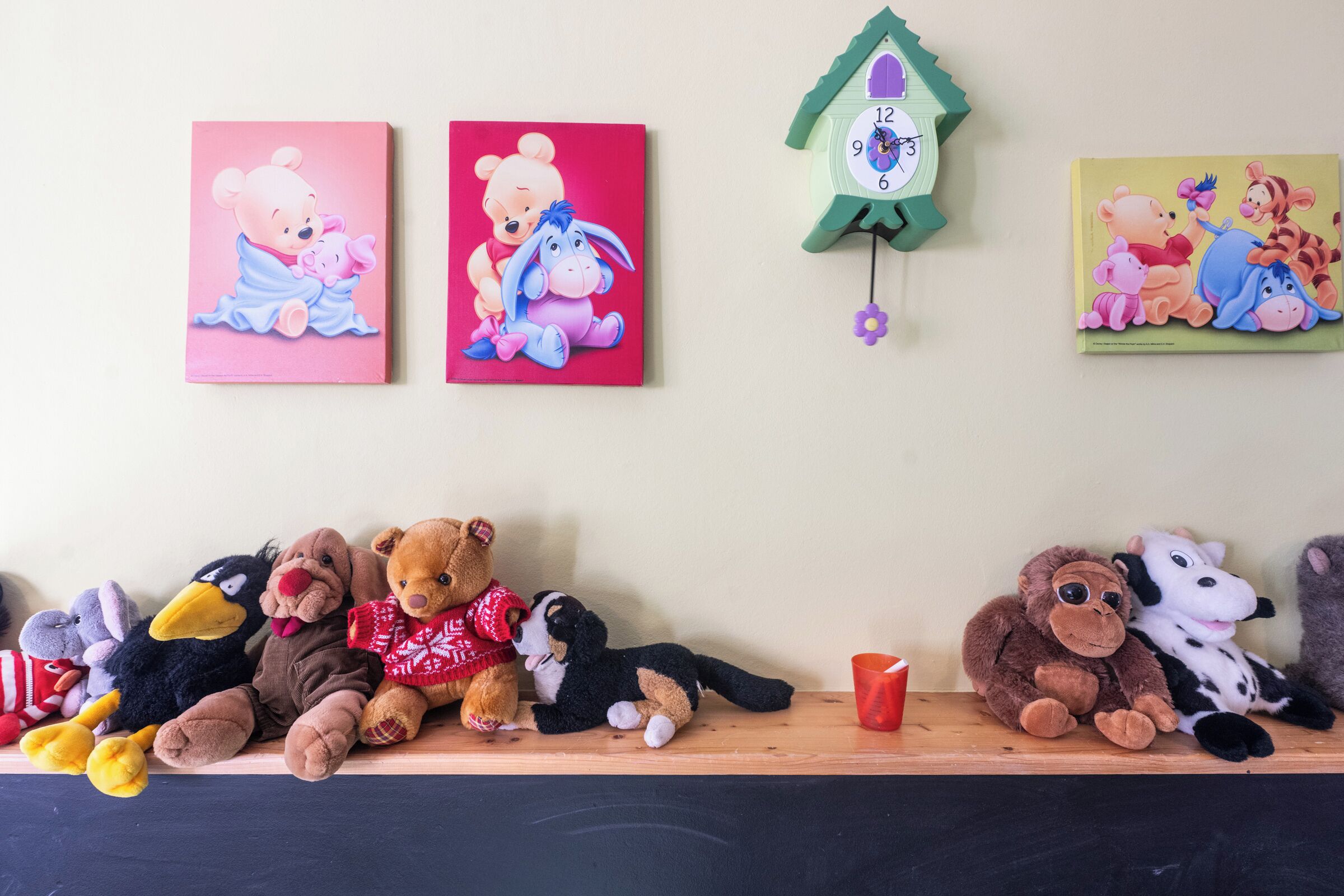Un estante con varios peluches y dos relojes de pared.