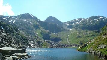 A mountainous landscape with a lake, rocky shores, and snow-capped peaks.