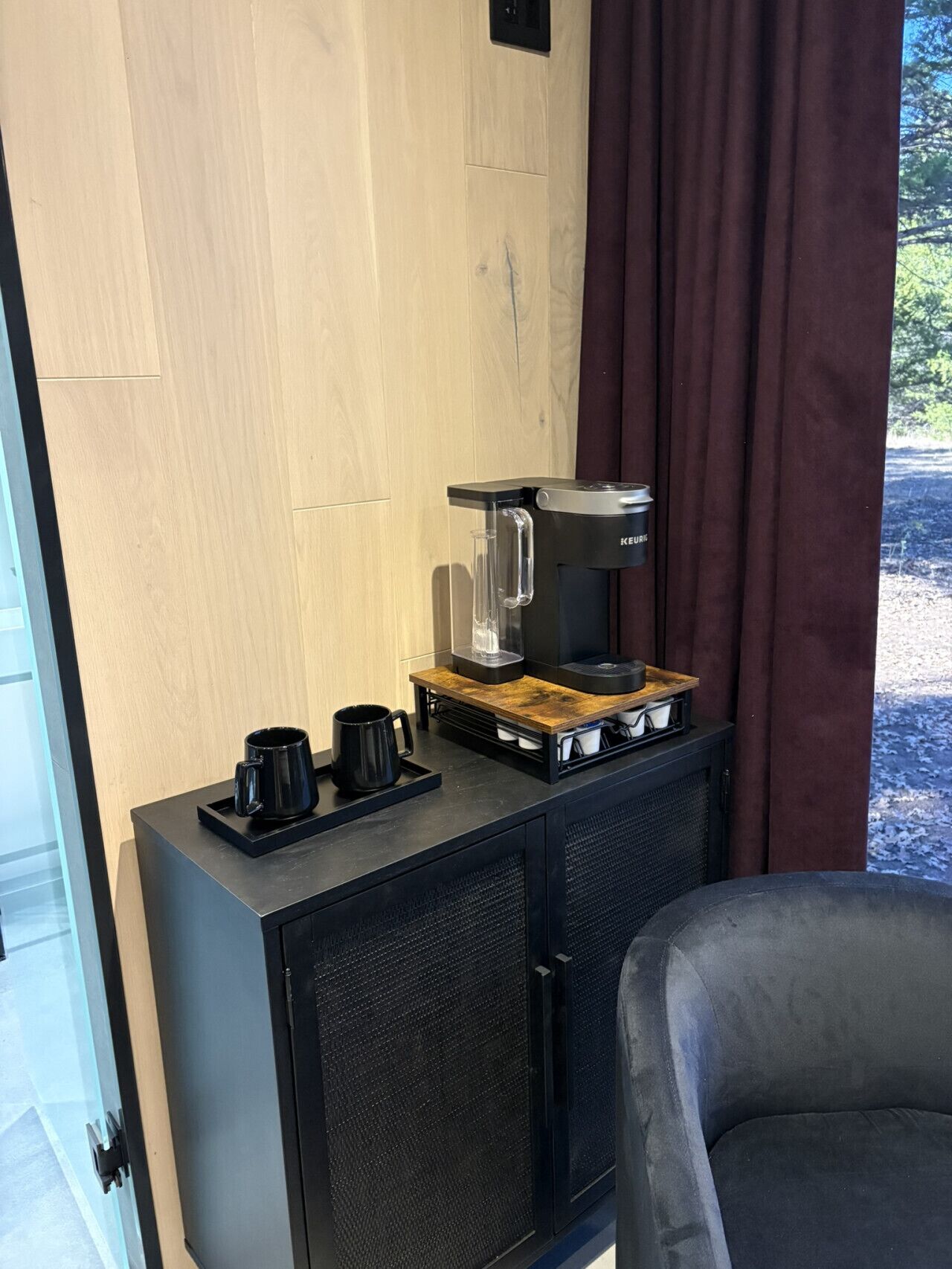 A kitchenette with a coffee maker, a coffee pot, and a tray with two mugs.