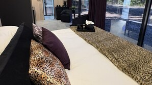 Une chambre d’hôtel moderne dotée d’un grand lit, d’un coin salon avec une table et offrant une vue sur l’extérieur.