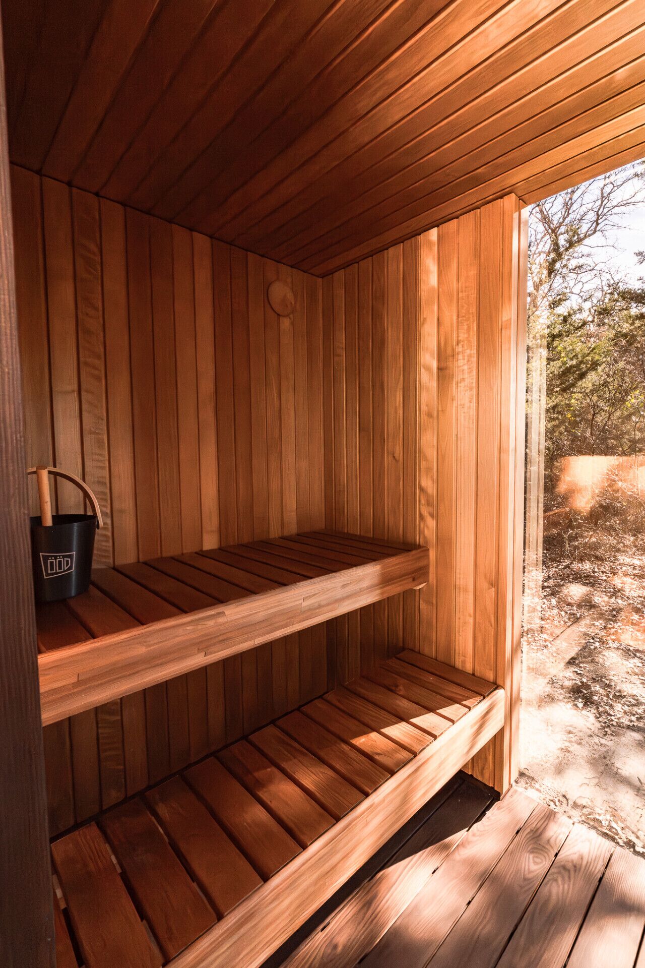 Una sauna de madera con dos bancos y un cubo negro con un logotipo.