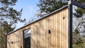 Une cabane en bois avec un jacuzzi, un barbecue et une terrasse.
