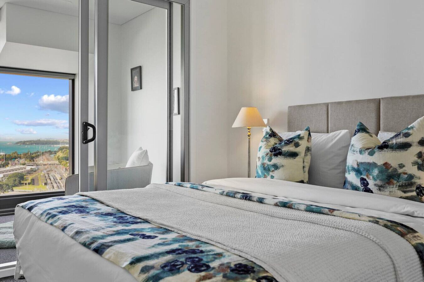 A hotel room with a large bed, a view of the city, and a balcony.
