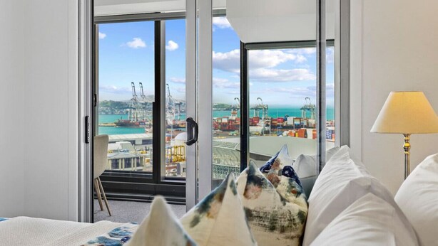A hotel room with a large window offering a view of a port with cranes and containers. - Modern Haven w Sea and City Views nr Spark Arena (Auckland CBD)