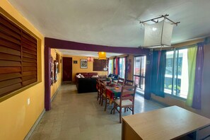 A dining area with a wooden table and chairs, a sofa, and a hanging light fixture. - 01 Casa Naranja in Isla Mujeres (Isla Mujeres)