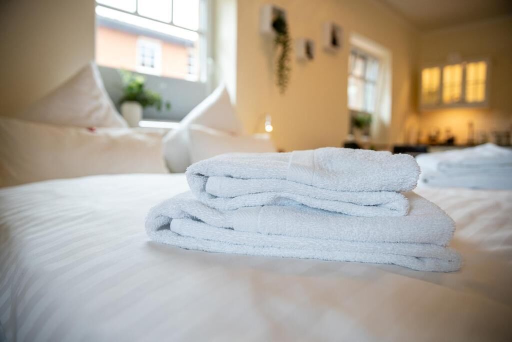 A neatly made bed with folded white towels in a hotel room.
