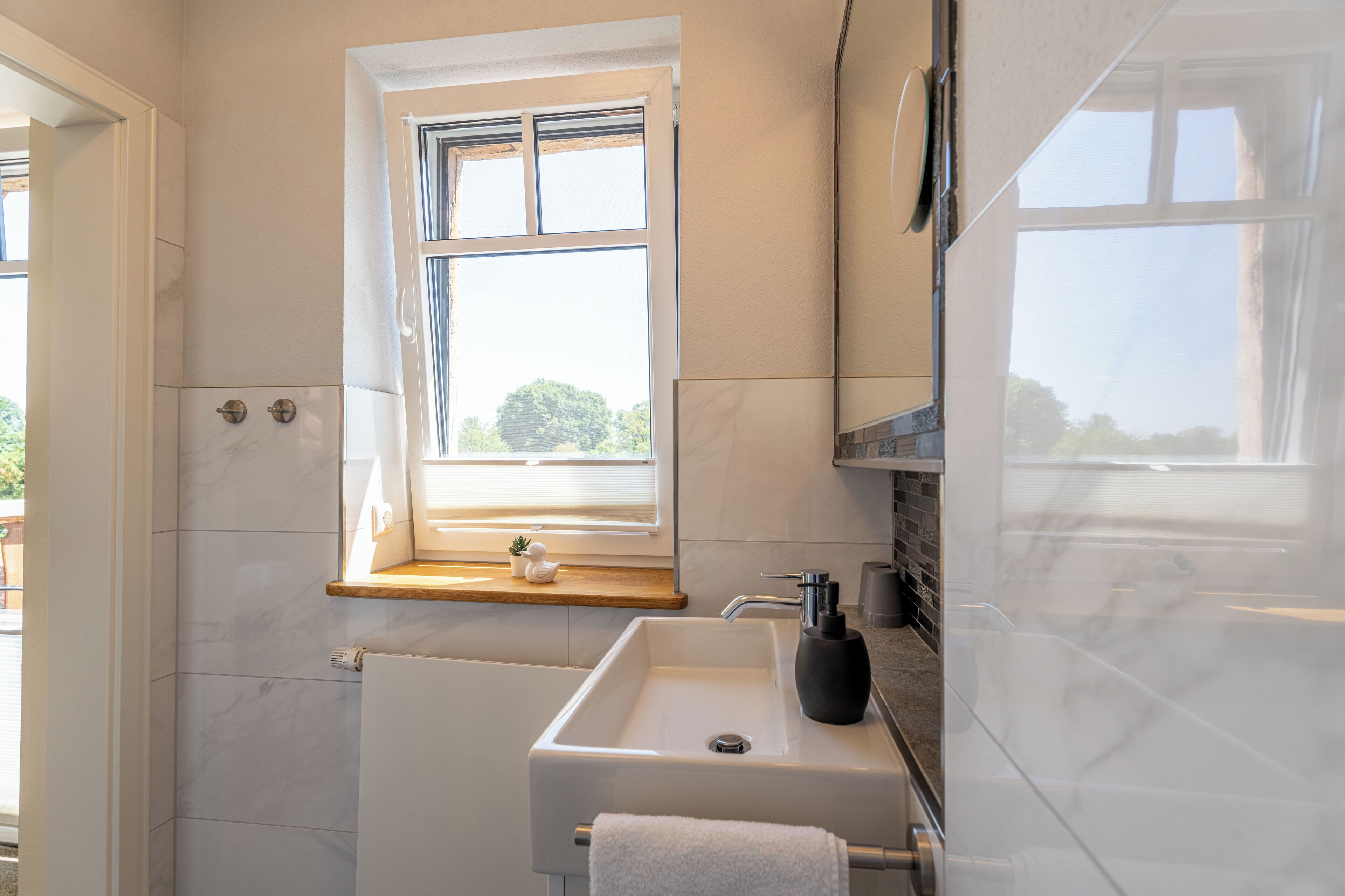 Un baño con ventana, lavabo y espejo.