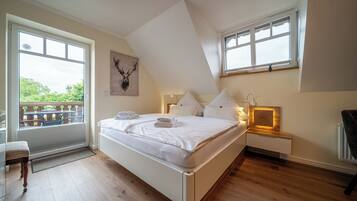 Une chambre avec un grand lit, une fenêtre, un plancher en bois et une vue sur la verdure.
