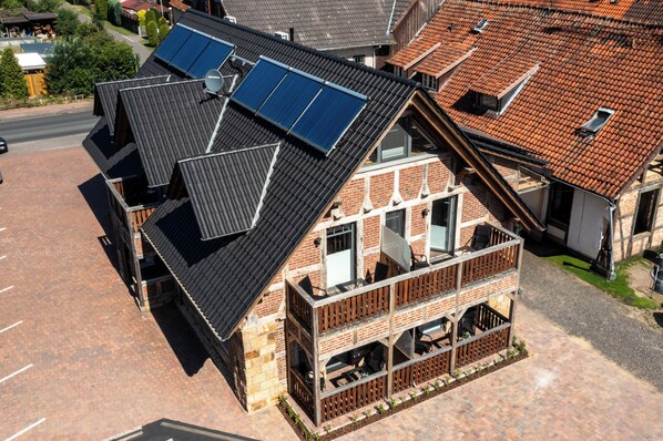 A two-story building with a sloped roof, solar panels, and a balcony with outdoor seating. - Rehburger Landhaus (Rehburg-Loccum)