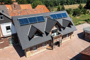 Een gebouw met twee verdiepingen, een schuin dak, zonnepanelen en een bakstenen gevel.