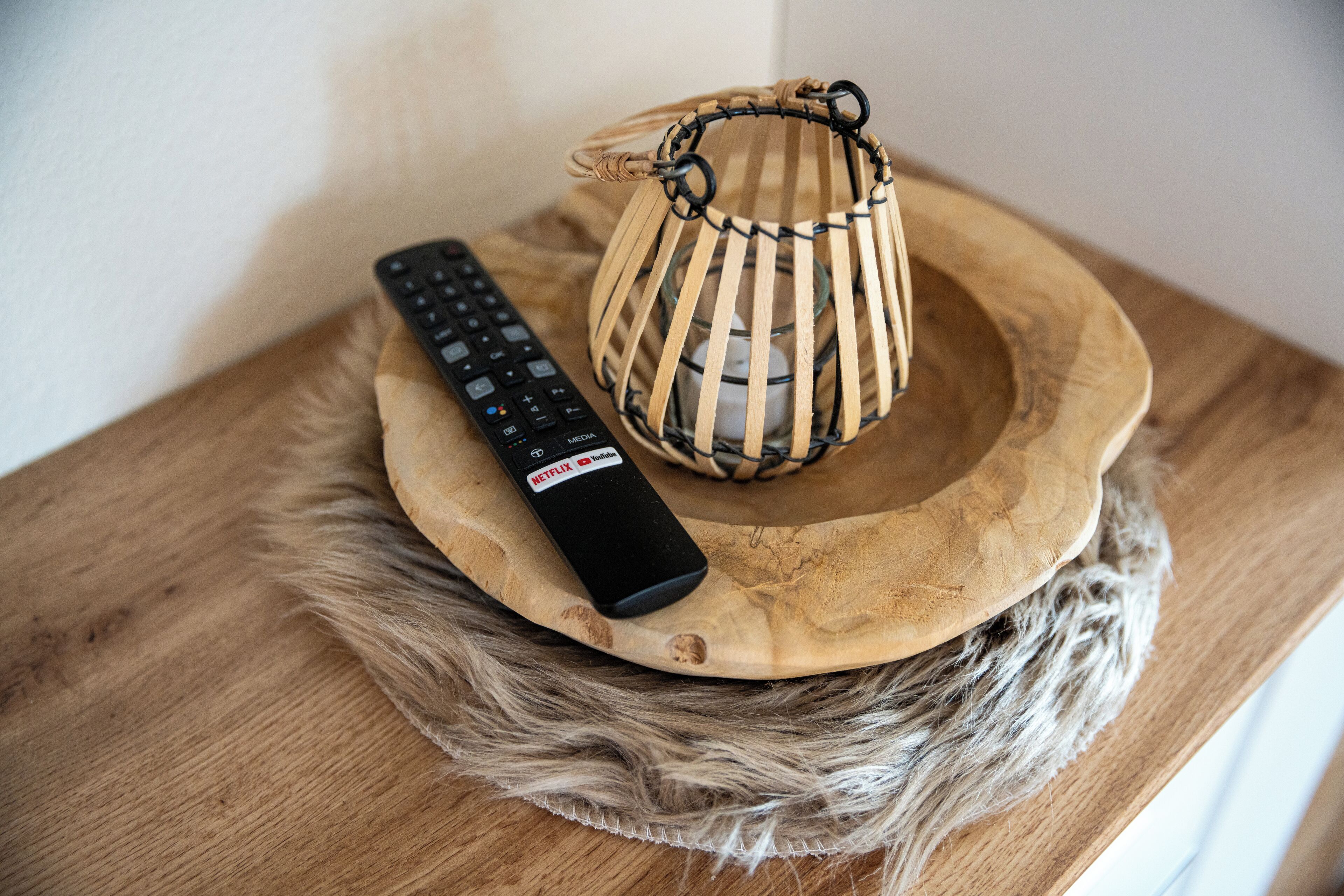 A wooden table with a remote control and a woven basket on it.