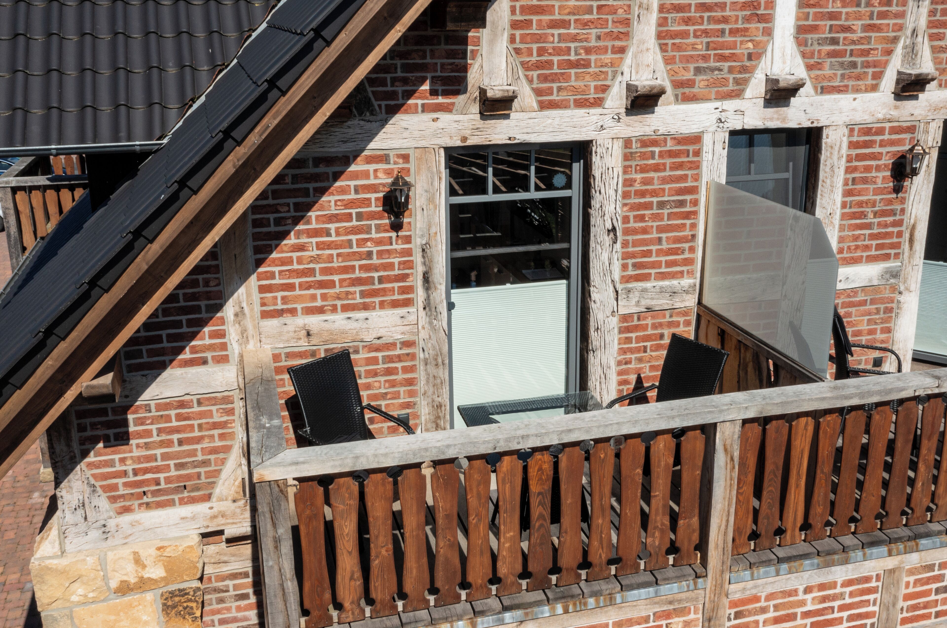 A brick building with a wooden balcony, a window, and a door.