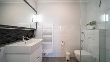 Een moderne badkamer met een witte wastafel, spiegel en toilet.