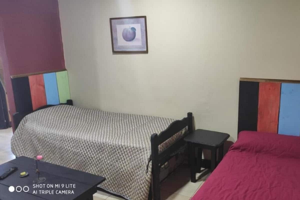 Une petite pièce simple, avec deux lits, une petite table et une chaise.