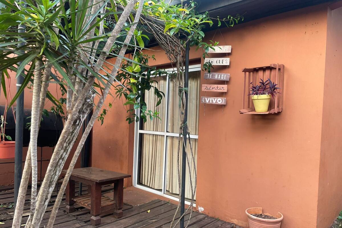 Une terrasse en bois avec un banc, un pot de fleurs et une enseigne fixée au mur avec du texte.