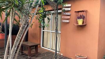 A wooden deck with a bench, a potted plant, and a wall-mounted sign with text.