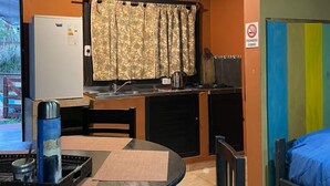 A compact room with a kitchenette, a dining table, a single bed, and a TV. - Apart Del Huesped  (Puerto Iguazú)