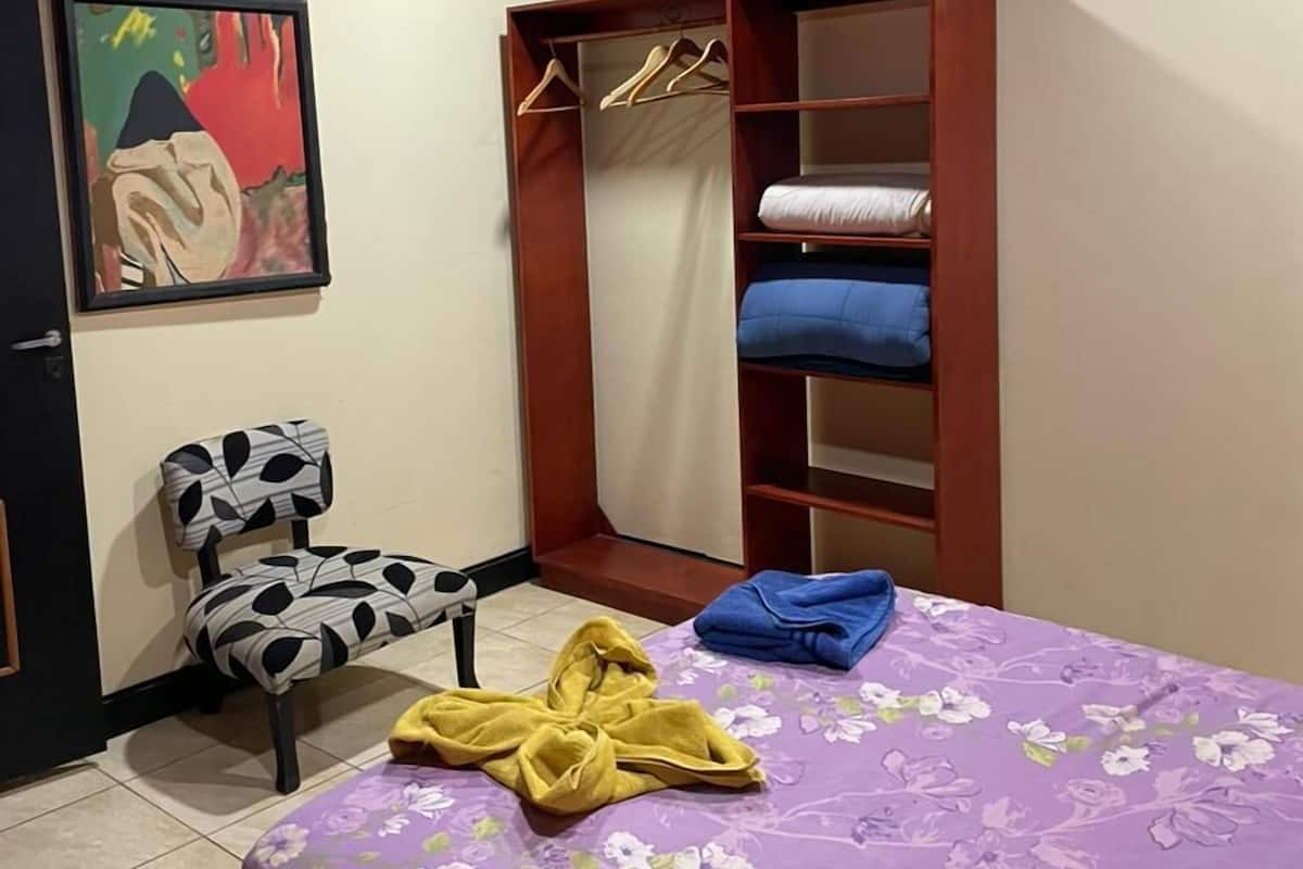 Une chambre à coucher avec un lit, une chaise, une armoire et un tableau accroché au mur.