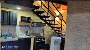 Una cocina con armarios oscuros, un microondas, una estufa y un refrigerador.