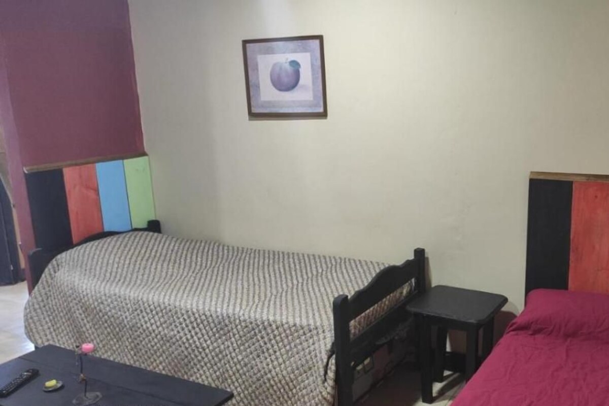 Une petite pièce simple, avec deux lits, une petite table et une chaise.