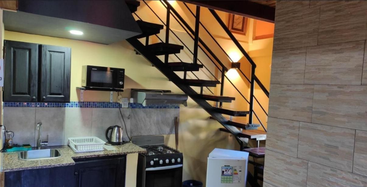 Una cocina con armarios oscuros, un microondas, una estufa y un refrigerador.
