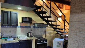 A kitchen with dark cabinets, a microwave, a stove, and a refrigerator. - Apart Del Huesped  (Puerto Iguazú)