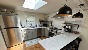 A modern kitchen with a stainless steel refrigerator, a microwave, an oven, and a coffee machine.