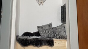 A small, cozy room with a wooden platform bed, two patterned pillows, and a heart-shaped wall decoration. - Vacation apartment on the Danube cycle path (Untermarchtal)