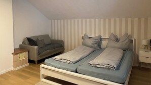 A bedroom with a bed, a sofa, a nightstand, and a lamp. - Vacation apartment on the Danube cycle path (Untermarchtal)