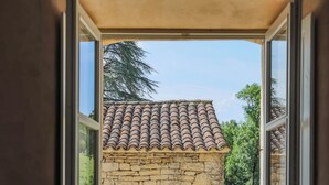 Ein Steinhaus mit Ziegeldach, durch ein offenes Fenster betrachtet.