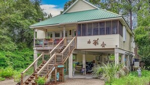 A two-story house with a covered porch, a staircase, and a view of the surrounding greenery. - Beach/Marina/Walking trails and more… (Carrabelle)