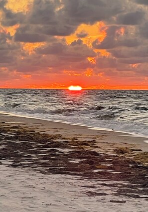 Ein Strand mit Wellen und einem Sonnenuntergang.