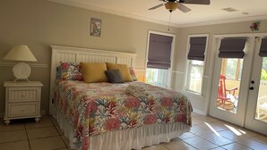 A bedroom with a bed, a nightstand, a ceiling fan, and a window with a view of the outside. - Beach/Marina/Walking trails and more… (Carrabelle)