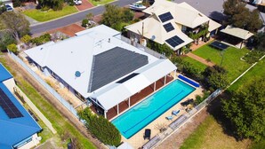 Una propiedad residencial con piscina, paneles solares y un patio cubierto.