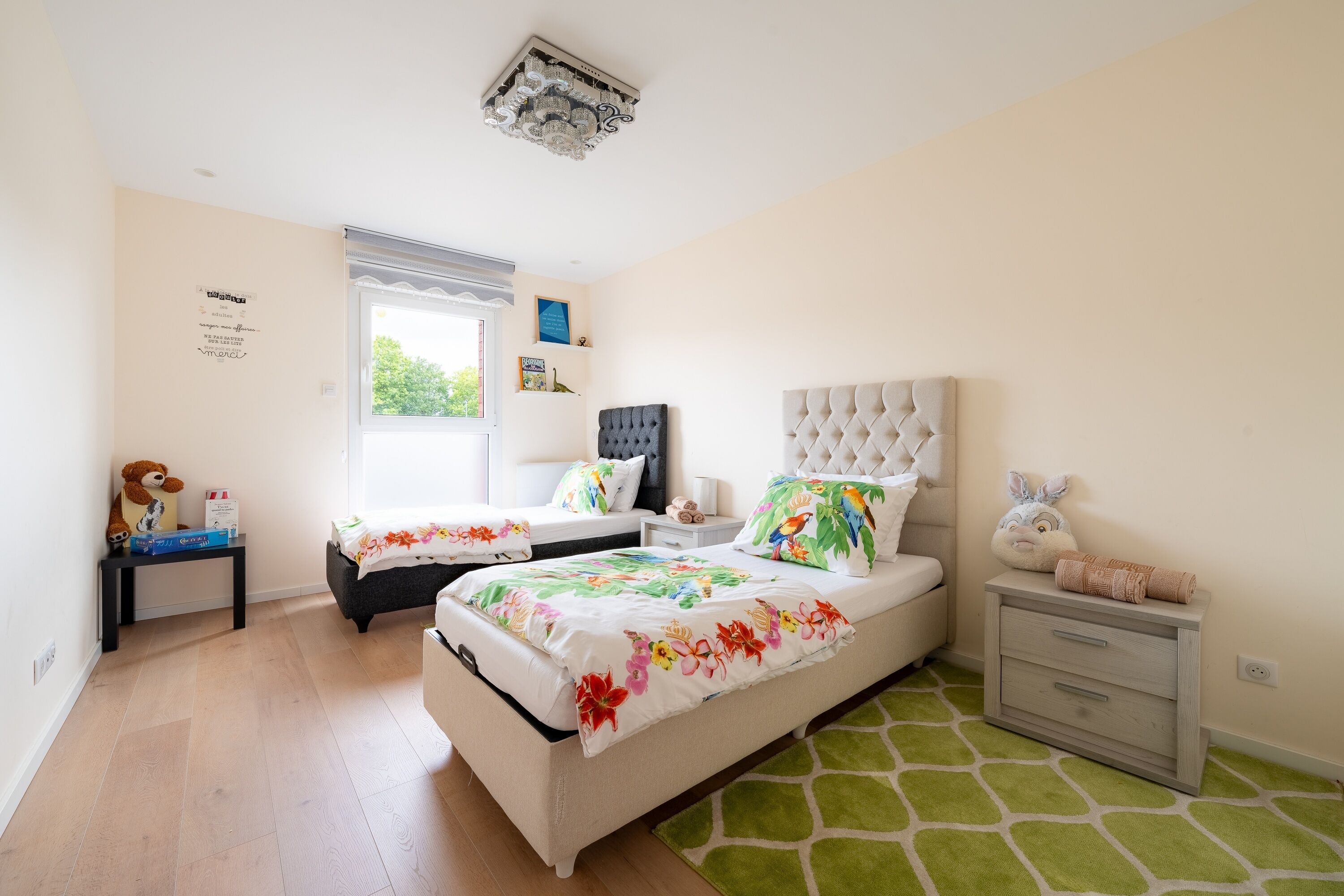 Een slaapkamer met twee bedden, een raam, een nachtkastje en een kledingkast.