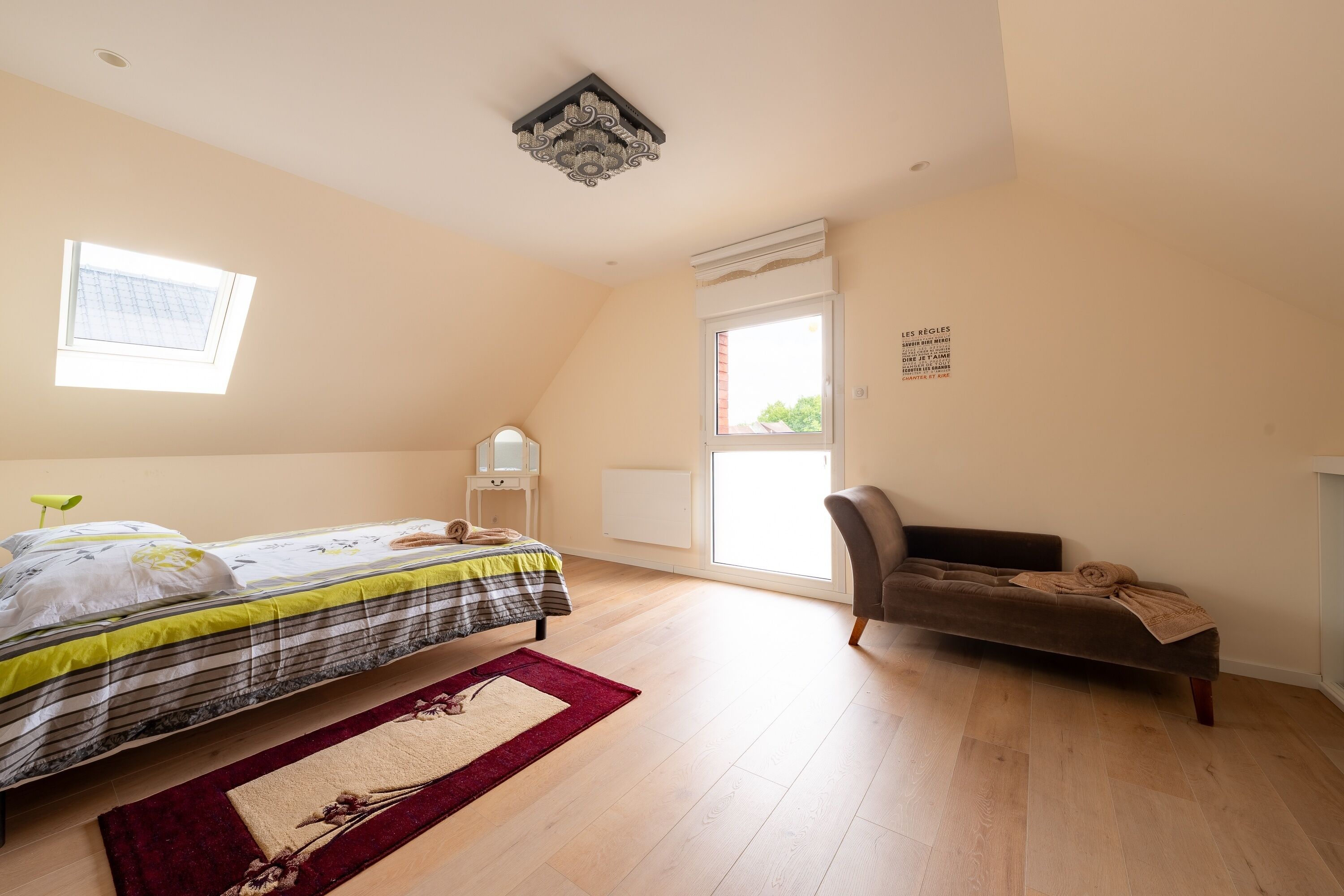 Une chambre à coucher avec un lit, une chaise, une fenêtre et un radiateur.