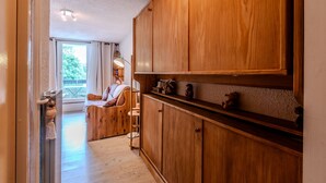 A wooden cabinet with shelves, a chair, and a view of a balcony with a table and chairs.