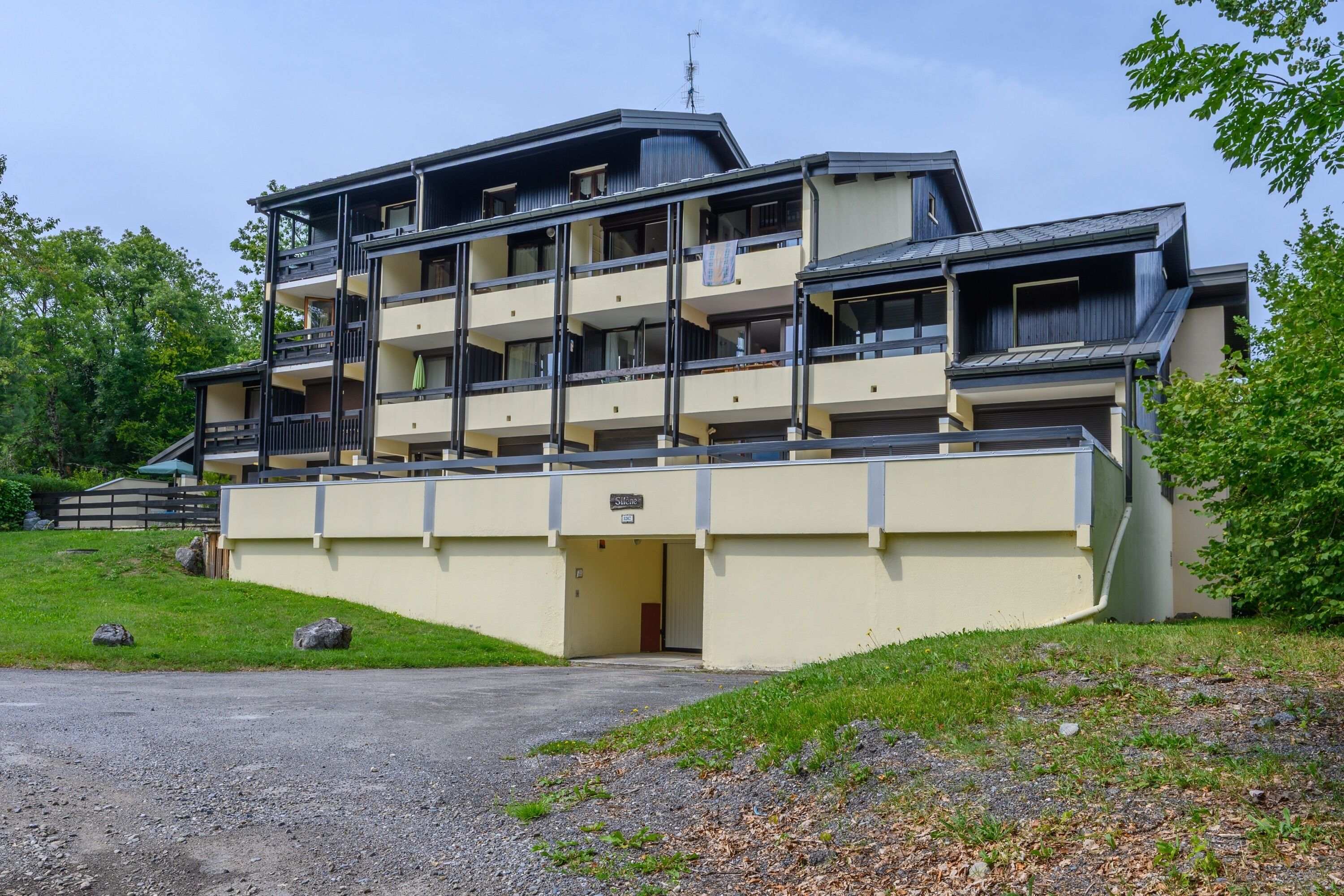 Un hôtel à plusieurs étages, doté de balcons, d’un toit plat et d’un espace de stationnement.