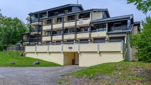 A multi-story hotel with balconies, a flat roof, and a parking area.