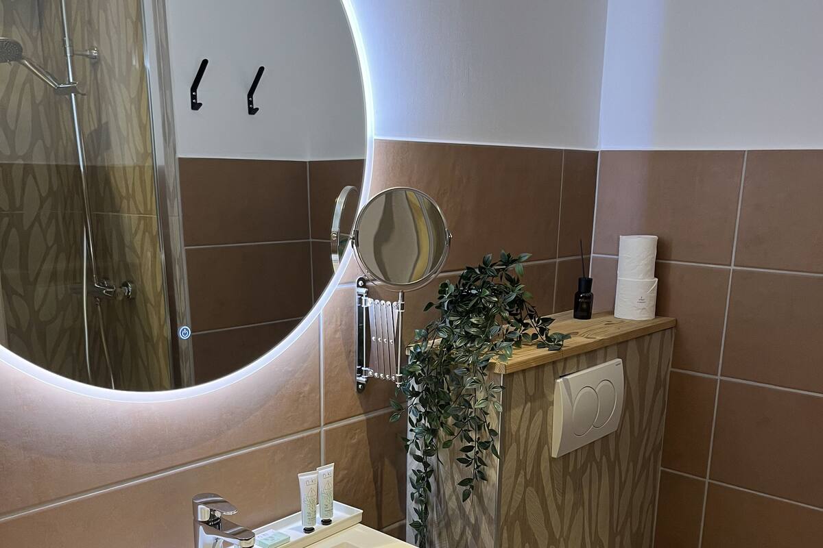 A bathroom with a round mirror, a sink, a toilet, and a towel rack.