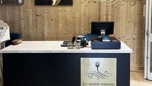 Een receptiebalie met een houten achtergrond, een klok en een menubord.